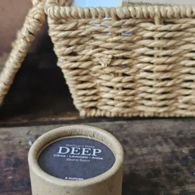 DEEP beard balm by Backyard Bees styled with other men’s grooming products in a rustic setting.