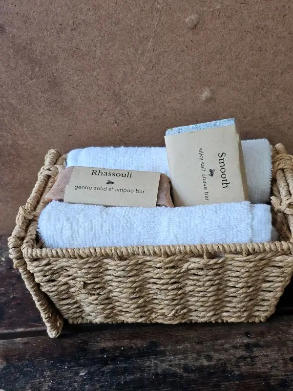 Rhassouli shampoo bar and Smooth shave bar in a basket with soft white towels.