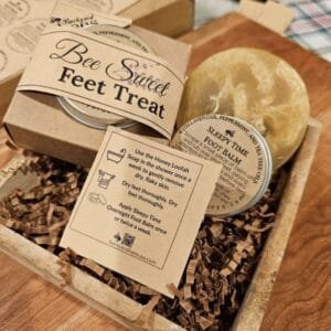 honey loofah foot soap and foot balm tin in a wooden tray