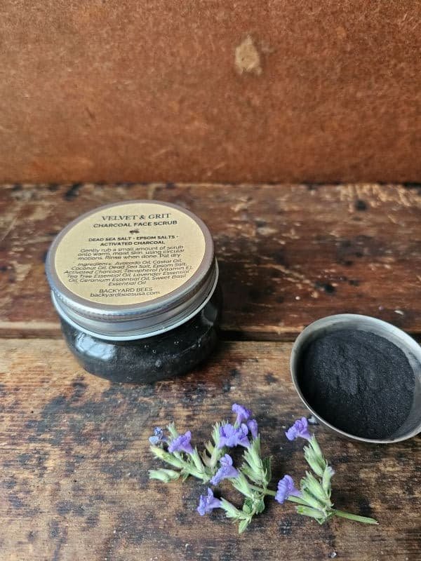 Velvet & Grit charcoal face scrub styled with lavender and raw ingredients on rustic wood background