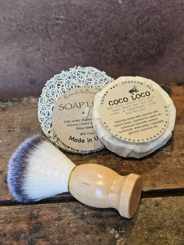 Coco-Loco-Flat-Lay Coco Loco vegan shave set on rustic wood table with kraft backdrop, featuring shave brush and vegan shave bar on soap lift.