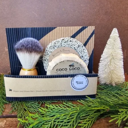 Coco Loco Holiday Coco Loco vegan shave gift set displayed with cedar greenery and seasonal bottle brush tree for holiday gift presentation.