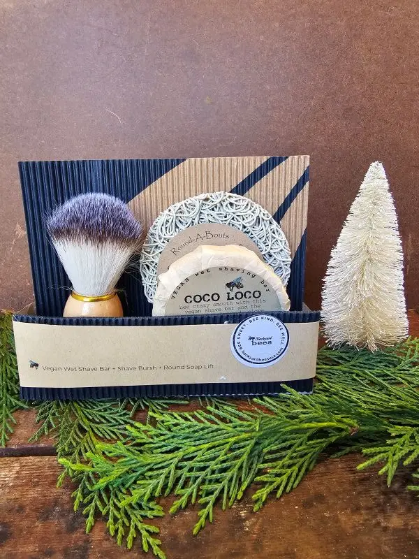 Coco Loco Holiday Coco Loco vegan shave gift set displayed with cedar greenery and seasonal bottle brush tree for holiday gift presentation.