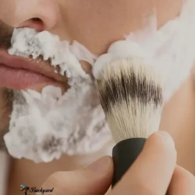 Close-up of a man applying shaving lather with a shave brush, demonstrating the creamy foam from the Coco Loco vegan shave bar.