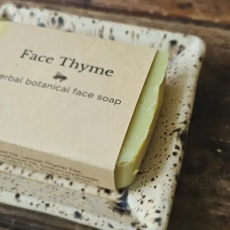 Close-up of Face Thyme Facial Soap with herbs on rustic soap dish