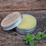 Sleepy Time Foot Balm tin open on rustic table with fresh herbs
