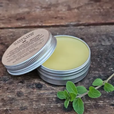 Sleepy Time Foot Balm tin open on rustic table with fresh herbs