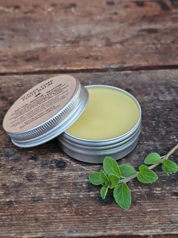 Sleepy Time Foot Balm tin open on rustic table with fresh herbs