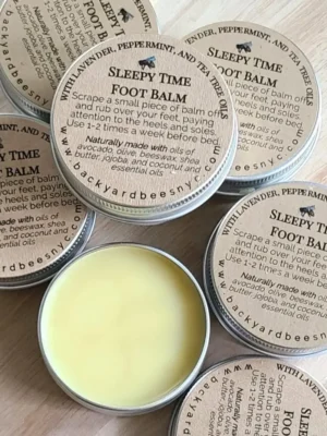 round yellow foot balm tin, open, surrounded by closed tins