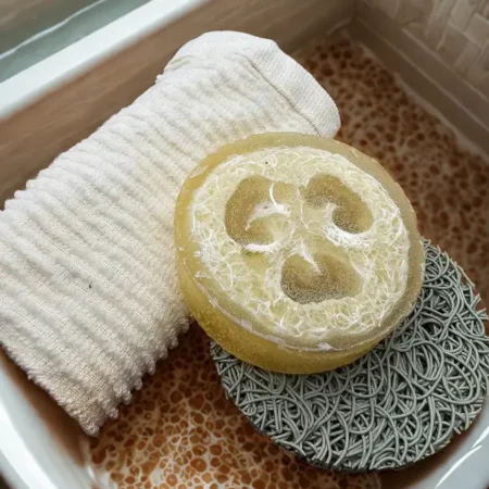 Honey loofah soap bar with natural sponge embedded, shown on washcloth