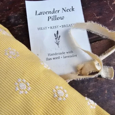 Close-up of butter yellow lavender neck pillow fabric with white embroidered flowers