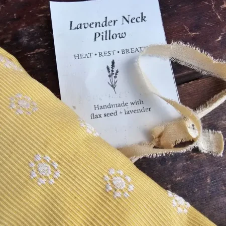 Close-up of butter yellow lavender neck pillow fabric with white embroidered flowers