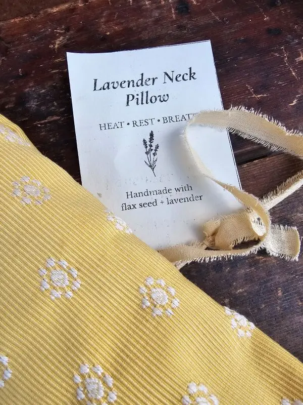 Close-up of butter yellow lavender neck pillow fabric with white embroidered flowers