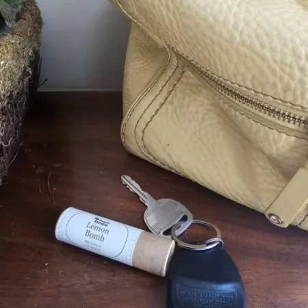 Lemon Bomb lip balm beside everyday essentials, ready to tuck into a purse or pocket