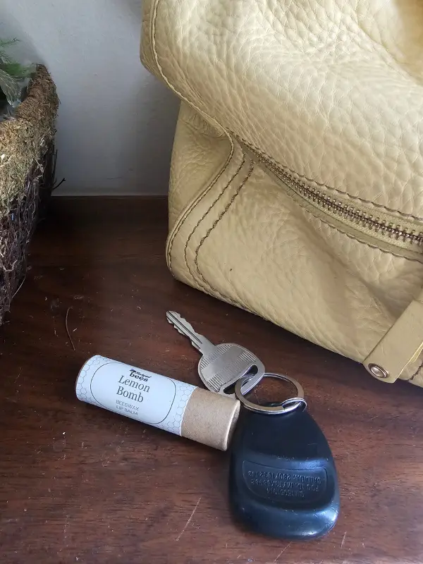 Lemon Bomb lip balm beside everyday essentials, ready to tuck into a purse or pocket