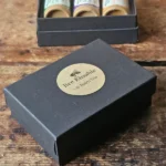 small black box with Backyard Bees Bee Kissable Lip Balm Trio printed on kraft sticker