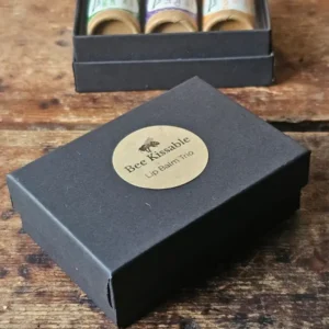 small black box with Backyard Bees Bee Kissable Lip Balm Trio printed on kraft sticker