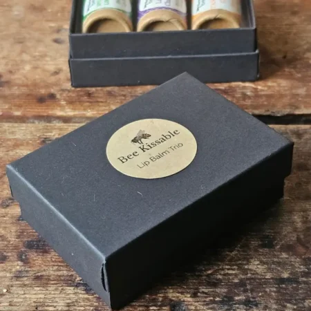 small black box with Backyard Bees Bee Kissable Lip Balm Trio printed on kraft sticker
