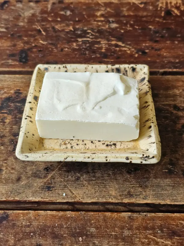 white salt water bar of soap on rustic ceramic soap dish