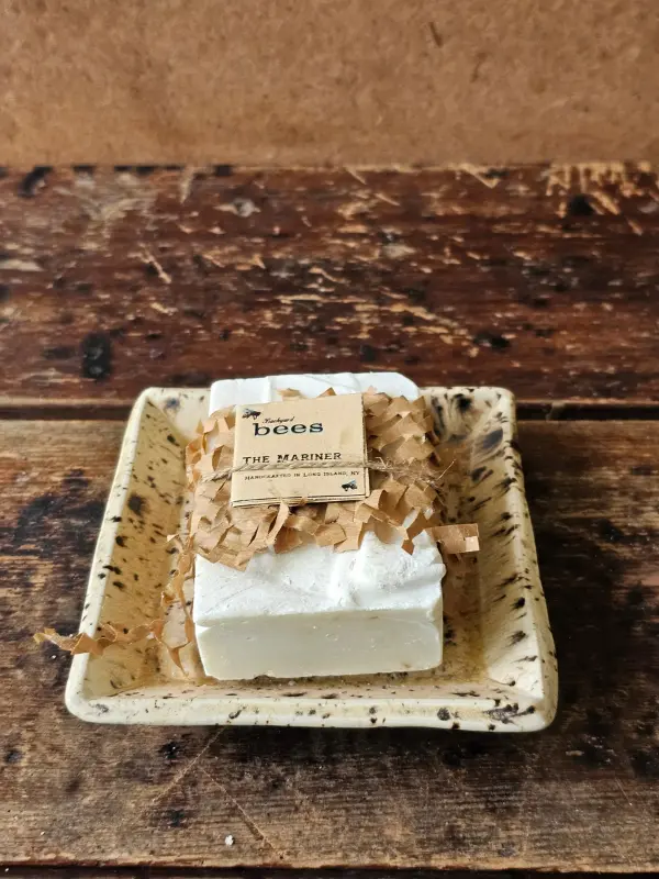 The Mariner soap bar in upcycled packaging sitting on rustic soap dish