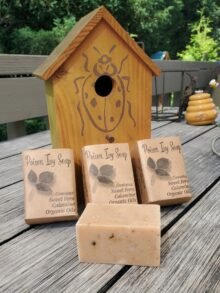 3 bars of poison ivy soap leaning again a yellow bird house