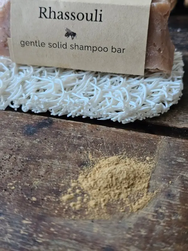 pile of rhassoul brown clay next to Rhassouli shampoo bar