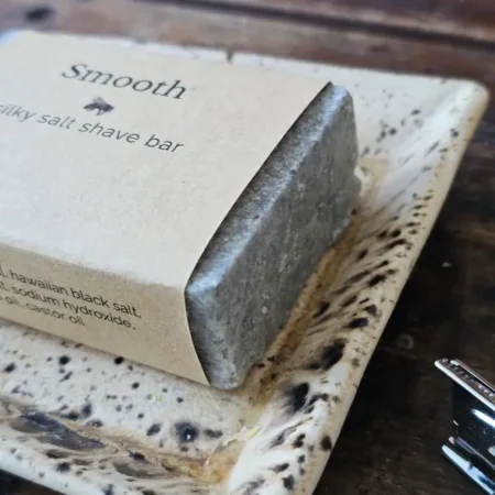 Close up of SMOOTH shave soap on rustic soap dish with stainless steel safety razor