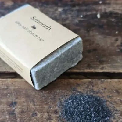 side view of SMOOTH ladies shave soap with pile of Hawaiian black sea salt