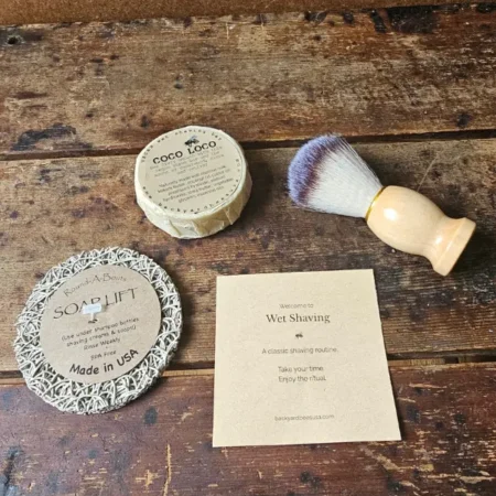 flat lay of Coco Loco vegan wet shave bar, shave brush, soap lift and beginners instruction guide by Backyard Bees
