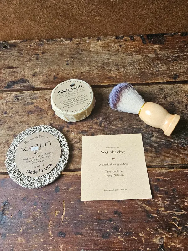 flat lay of Coco Loco vegan wet shave bar, shave brush, soap lift and beginners instruction guide by Backyard Bees