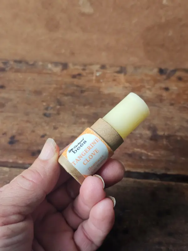 Open Tangerine Clove beeswax lip balm in a recyclable paper tube.
