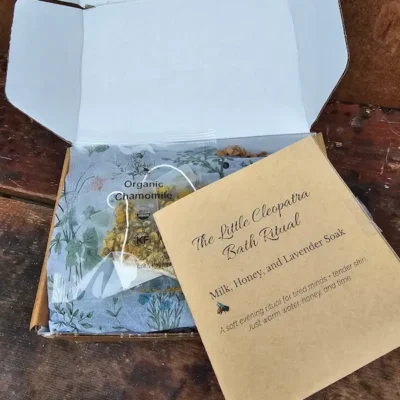The Cleopatra Bath Ritual booklet resting on botanical tissue, inviting a quiet evening self-care moment.