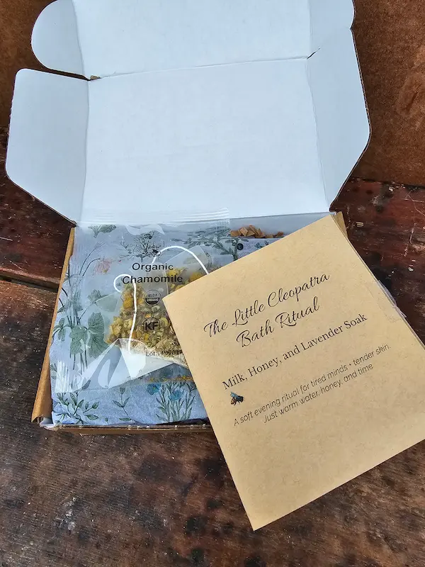 The Cleopatra Bath Ritual booklet resting on botanical tissue, inviting a quiet evening self-care moment.