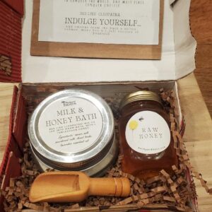 a milk and honey bath gift set box with a jar of honey and a wooden scoop