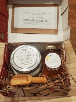 a milk and honey bath gift set box with a jar of honey and a wooden scoop