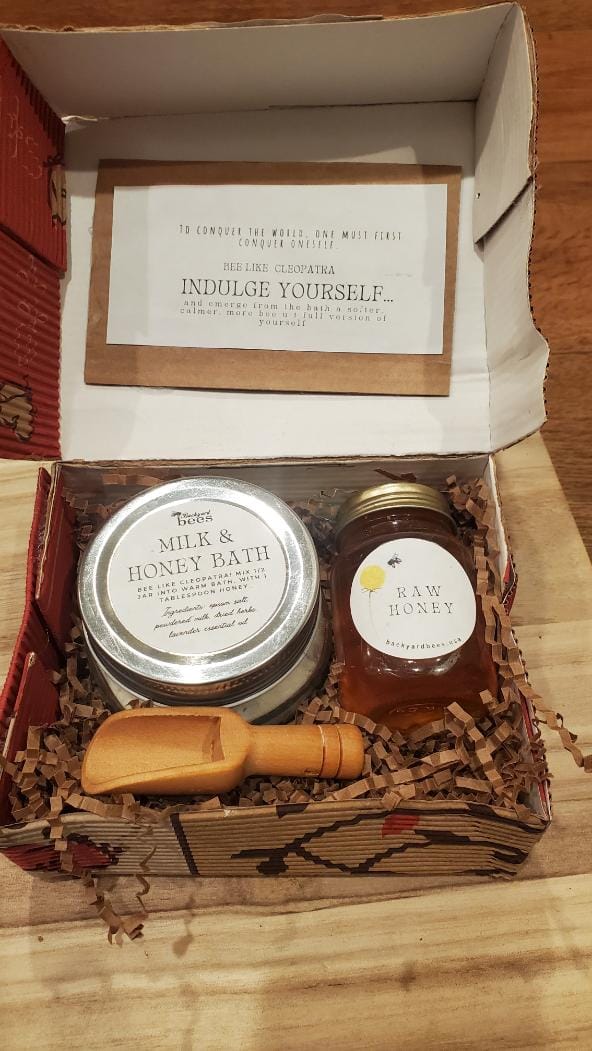 a milk and honey bath gift set box with a jar of honey and a wooden scoop