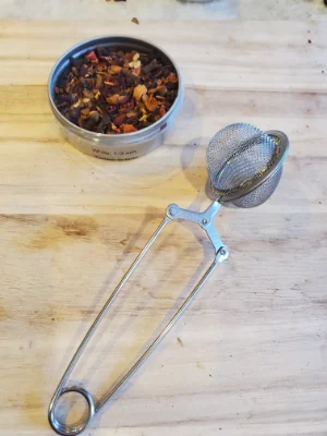 Tea-Strainer tea strainer with open tin of loose tea