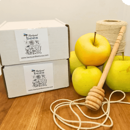 Two Rosh Hashanah honey gift boxes, apples, honey dipper, twine.