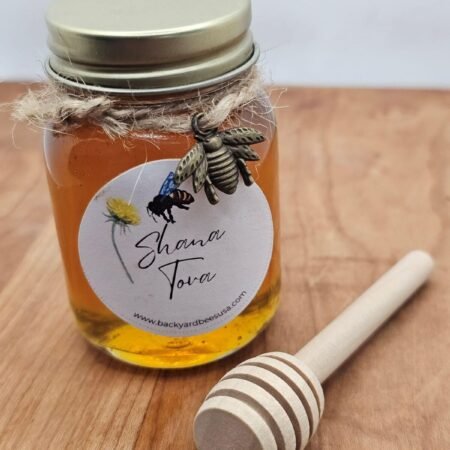 Jar of honey with wooden dipper, wrapped in twine with bee charm