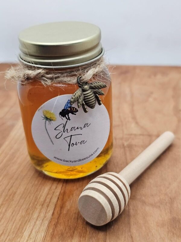 Jar of honey with wooden dipper, wrapped in twine with bee charm