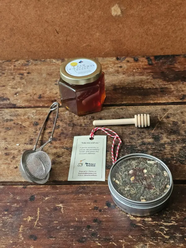 Contents Holiday Take Tea And See Holiday Take Tea & See gift contents: wildflower honey, loose-leaf tea tin, metal tea strainer, wooden honey dipper, and gift tag.