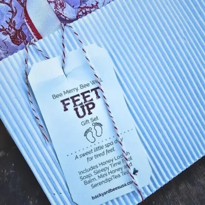 Hand made white ribbed upcycled holiday gift bag with red tissue, salvaged candy cane ribbon, and Feet Up gift tag.