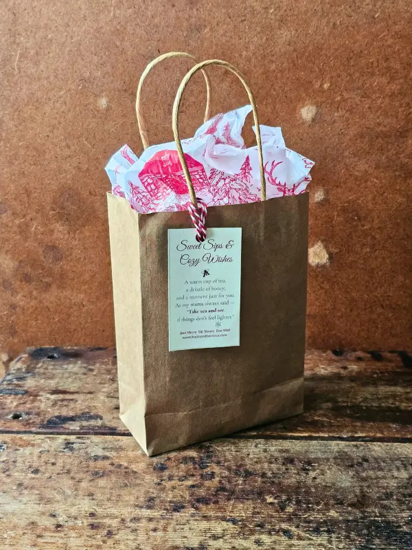Holiday Take Tea And See Bag Holiday Take Tea & See gift in a kraft bag with red-and-white holiday tissue and a Sweet Sips & Cozy Wishes tag.