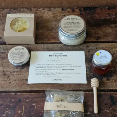 Bee Barefoot gift set contents laid out with foot soak, foot care duo, honey, tea, dipper, and ritual card