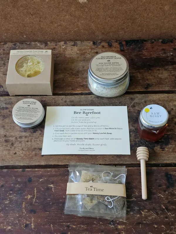 Bee Barefoot gift set contents laid out with foot soak, foot care duo, honey, tea, dipper, and ritual card