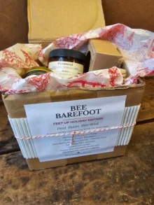 Bee Barefoot Holiday Edition gift box with cranberry label and upcycled holiday packaging.