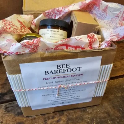 Bee Barefoot Holiday Edition gift box with cranberry label and upcycled holiday packaging.