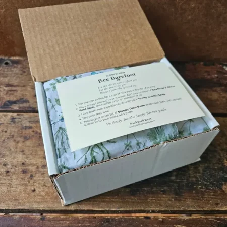 Bee Barefoot ritual card resting on botanical tissue inside the gift box