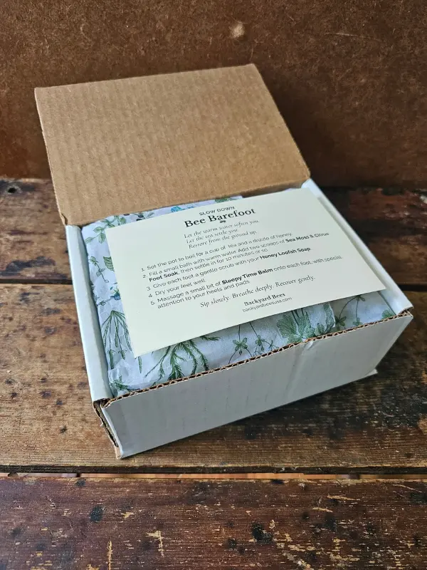 Bee Barefoot ritual card resting on botanical tissue inside the gift box