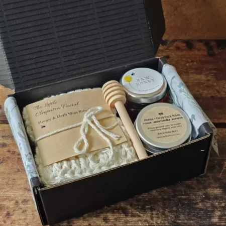 Cleopatra Mini gift set arranged inside an open black box with washcloth, face mask, honey, and dipper